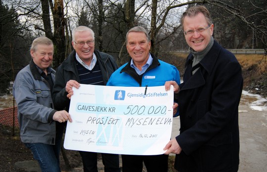 Steinar Heller, Rolf Dillevik, Steinar Svendsen og Erik Unaas med sjekken foran den frådende Susebakkefossen. (Foto: Adrian Sellstrøm)